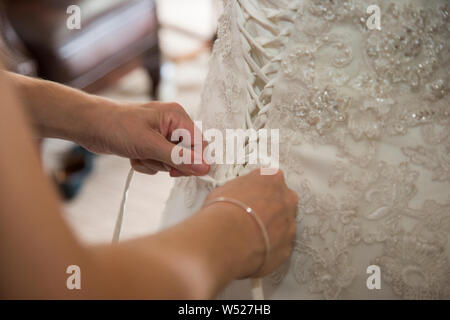 Wedding dress being done up on a Brides wedding day, close up of wedding dress being done up before the ceremony Stock Photo