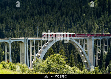 Langwies, GR / Switzerland - 24. July, 2019: the Rhaetian railway crosses the Langwies Viaduct over a deep ravine on the Chur - Arosa line Stock Photo