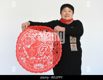 Chinese folk artist Li Yinjie shows a paper-cutting artwork featuring pig to mark the upcoming Spring Festival or the Chinese New Year (Year of the Pi Stock Photo