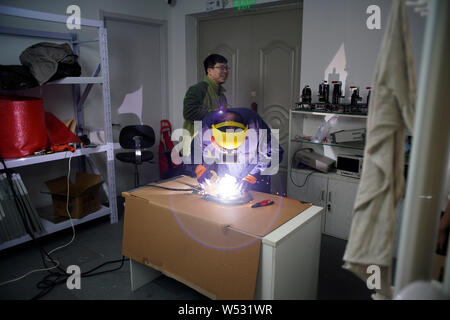 The father of Chinese Peppa Pig fan Han Bing welds a steel rod on a partially-finished 'Iron Peppa' model as the smiling mouth at their workshop in Be Stock Photo