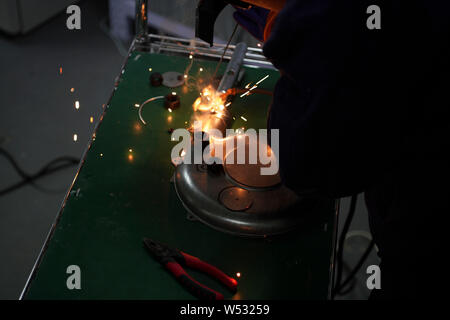 The father of Chinese Peppa Pig fan Han Bing welds two nuts on a partially-finished 'Iron Peppa' model as nostrils at their workshop in Beijing, China Stock Photo