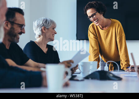 Group of businesspeople smiling during a meeting in conference room. Business people having casual discussion during meeting in board room. Stock Photo