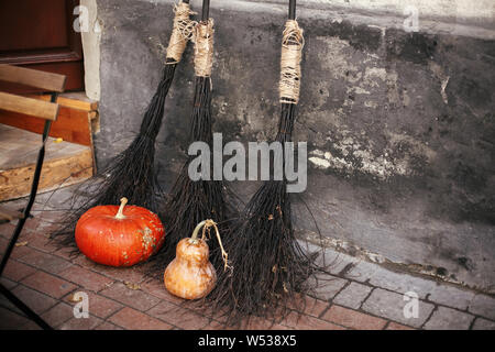 Pumpkins and witch brooms in city street, holiday decoration of store fronts and buildings. Halloween street decor. Space for text. Trick or treat. Ha Stock Photo