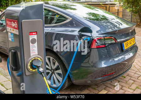 External electric car charging point at the side of a canal in Amsterdam, Holland charging a Tesla car. Stock Photo