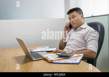 Asian businessman answer the phone call in office Stock Photo