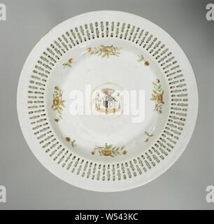 Plate with the arms of the Cornets de Groot family, Porcelain plate with openwork (openwork) border, painted on the glaze in red, green, brown, black and gold. On the shelf in a medallion the coat of arms of the Cornets de Groot family in black and gold. The weapon is divided into four parts: 1. and 4. three horns with in the center a heart shield with a black background and a golden star, 2. and 3. on a black background three golden byzantines or balls and three crows. Above the coat of arms is a crown with eleven pearls. There are two wild men on either side of the shield holding a club. Stock Photo