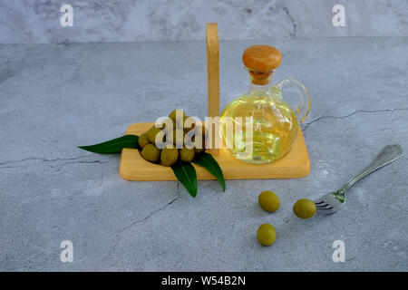 Closeup fork with olives, Set of olive oil and leaf on marble background, Glass bottle with olive oil on cement table Stock Photo