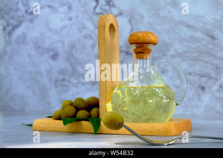 Closeup fork with olives, Set of olive oil and leaf on marble background, Glass bottle with olive oil on cement table Stock Photo
