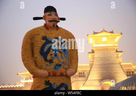 A five-meter-tall straw-made man featuring shape of Emperor Xuanzong of Tang stands in front of an ancient city gate to welcome tourists in Xiangyang Stock Photo