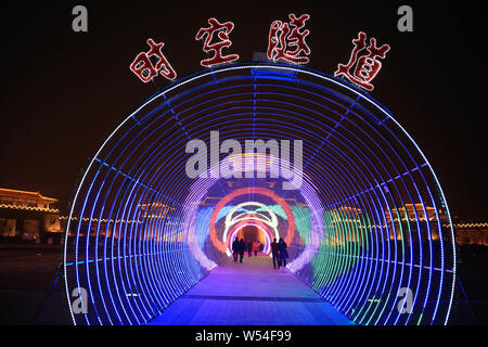 Visitors walk through a tunnel illuminated by colorful lights