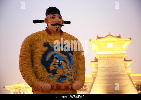 A five-meter-tall straw-made man featuring shape of Emperor Xuanzong of Tang stands in front of an ancient city gate to welcome tourists in Xiangyang Stock Photo