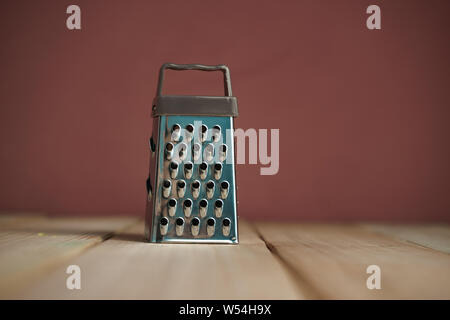 Close up beautiful new grater on a wooden table and brown wall background. Stock Photo