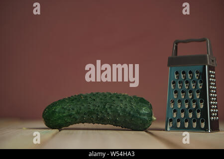 Close up beautiful new grater on a wooden table, brown wall background. Stock Photo