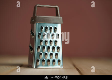 Close up beautiful new grater on a wooden table and brown wall background. Stock Photo