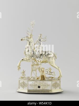 Table automaton in the form of Diana on a stag, Table automaton in the form of Diana on a deer, Diana, seated on a deer. Automatic silver, partly gold-plated. The deer, which has a removable head and wears a crown, is surrounded by openwork band ornament. Similar decorations around the eight-sided pedestal, on which all kinds of insects and animals are placed on a natural base, including two hunting dogs, a horseman and a hunter. A few holes point to other lost additions. Diana looks back. She wears a bow and an arrow quiver on the back and holds in her raised left hand the end of the chain Stock Photo