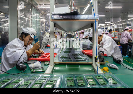 --FILE--Chinese workers manufacture electric products on the assembly line at a factory in Xiangxi Tujia and Miao Autonomous Prefecture, central China