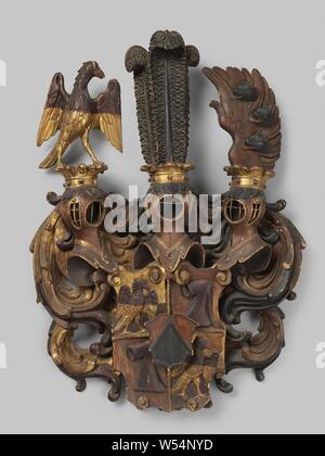 Coat of arms of wood, Wooden carved coat of arms, partly gilded and further painted in black, red-brown and violet. The coat of arms is quartered and shows an eagle in two fields and a hood in two fields. The shield also has an imposed heart shield. On the weapon are three crowned helmet signs with an eagle, three ostrich feathers and a wing, on which three wild boar heads. The whole is surrounded by symmetrical leaf work., anonymous, Zuid-Duitsland, c. 1500 - c. 1600, wood (plant material), gilding (material), gilding, h 110 cm × w 78 cm × d 18 cm × w 17 kg Stock Photo