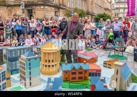 Glasgow, UK. 26 July 2019. Glasgow's annual biggest festival of free street entertainment attracts thousands of tourists and spectators to the Merchant City district to enjoy street theatre, mime performances, music and puppetry over a three day weekend. Actors from the Whalley Range All Stars street theatre from MANCHESTER perform the play 'All Days' Credit: Findlay/Alamy Live News Stock Photo