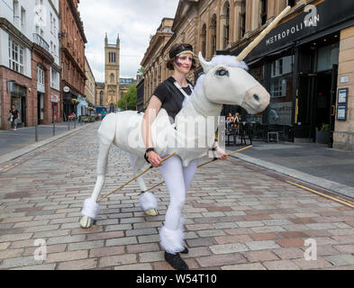 Glasgow, UK. 26 July 2019. Glasgow's annual biggest festival of free street entertainment attracts thousands of tourists and spectators to the Merchant City district to enjoy street theatre, mime performances, music and puppetry over a three day weekend. ELLA MACKAY from Glasgow performs street puppetry in the form of a unicorn. Credit: Findlay/Alamy Live News Stock Photo