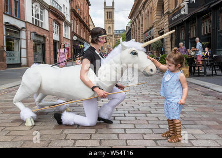 Glasgow, UK. 26 July 2019. Glasgow's annual biggest festival of free street entertainment attracts thousands of tourists and spectators to the Merchant City district to enjoy street theatre, mime performances, music and puppetry over a three day weekend. Two-year-old CHARLEY CAIRNS from Airdrie is fascinated by the unicorn puppet. Credit: Findlay/Alamy Live News Stock Photo