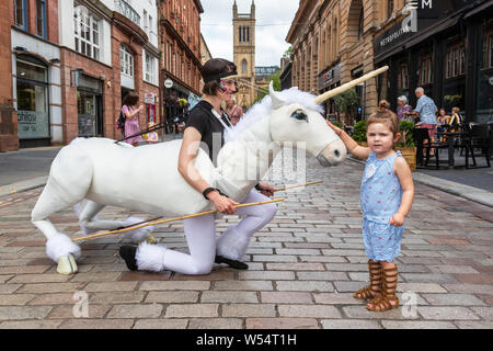 Glasgow, UK. 26 July 2019. Glasgow's annual biggest festival of free street entertainment attracts thousands of tourists and spectators to the Merchant City district to enjoy street theatre, mime performances, music and puppetry over a three day weekend. Two-year-old CHARLEY CAIRNS from Airdrie is fascinated by the unicorn puppet. Credit: Findlay/Alamy Live News Stock Photo