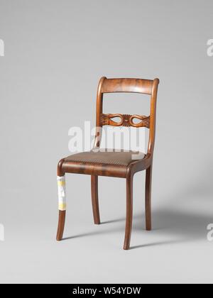 Chair with swans, Chair from a set of ten chairs and four armchairs of partly solid and partly glued mahogany on elm wood core. Loose upholstered seats. The square hind legs give way backwards. Nine chairs and an armchair have square, slightly rounded front legs, the rest have round articulated front legs. The stretched S-shaped ridges have a sculpted intermediate rail with a palette flanked by two swans bent back with the necks. The flat volute-shaped armrests run high in the back., anonymous, Netherlands, 1830, wood (plant material), mahogany (wood), oak (wood), textile materials, h 87 cm Stock Photo