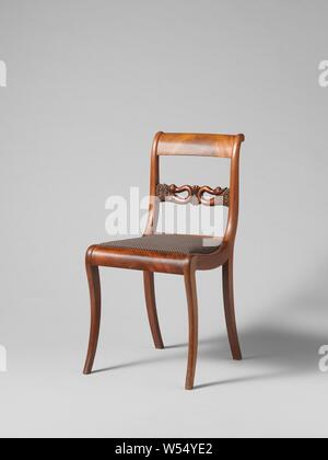 Chair with swans, Chair from a set of ten chairs and four armchairs of partly solid and partly glued mahogany on elm wood core. Loose upholstered seats. The square hind legs give way backwards. Nine chairs and an armchair have square, slightly rounded front legs, the rest have round articulated front legs. The stretched S-shaped ridges have a sculpted intermediate rail with a palette flanked by two swans bent back with the necks. The flat volute-shaped armrests run high in the back., anonymous, Netherlands, 1830, wood (plant material), mahogany (wood), elm (wood), textile materials, h 87 cm Stock Photo