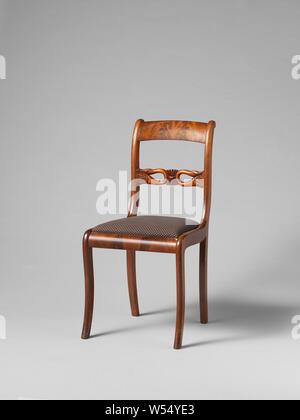 Chair with swans, Chair from a set of ten chairs and four armchairs of partly solid and partly glued mahogany on elm wood core. Loose upholstered seats. The square hind legs give way backwards. Nine chairs and an armchair have square, slightly rounded front legs, the rest have round articulated front legs. The stretched S-shaped ridges have a sculpted intermediate rail with a palette flanked by two swans bent back with the necks. The flat volute-shaped armrests run high in the back., anonymous, Netherlands, 1830, wood (plant material), mahogany (wood), elm (wood), textile materials, h 87 cm Stock Photo