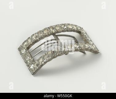 Buckle, rectangular and arched, consisting of center edge of alternately large oval and round rhinestones, framed by smaller rhinestones, Shoe buckle for a men's shoe, or a belt buckle of strassz in white metal. A curved rectangle consists of a center border of alternately large oval and round strasz diamonds, framed by smaller strasz diamonds. Close mounting of silver-plated copper (?). Two sharp teeth of iron for confirmation., anonymous, France, c. 1775 - c. 1800, paste (glass), iron (metal), h 2.6 cm × w 9.5 cm × d 5.1 cm Stock Photo