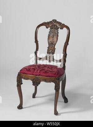 Chair, Chair made of carved walnut, the loose seat is covered with red velvet. The angled, profiled and stretched S-shaped front legs bear acanthus leaves at the bottom and rocaille and flower arrangements at the top, rear legs placed backwards. The back pillars, like the curved seat lines, show a hollow profile with C and S-shaped edge profiles, alternated with floral arrangements. The upper threshold carries a carved flower border, the scalloped middle leaf and the struts are decorated with a lot of floral work, flowers, ornament, anonymous, Amsterdam (possibly), c. 1750 - c. 1760, wood Stock Photo