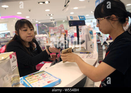 --FILE--A Chinese cashier scans the QR code through mobile payment service Alipay of Alibaba Group on the smartphone of a customer at the Sasa cosmeti Stock Photo