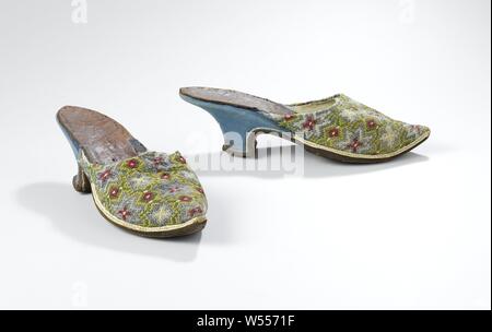 Mule with embroidered cover page silk on pattern, with pattern of blue star flowers on yellow ground with green network with red diamonds and white dots, Mule with cover page of embroidery of silk on pattern, with pattern of blue star flowers on yellow ground with green network with red diamonds and white dots. Model: Wide forefoot, pointed tip. The heel is halfway the geleng and is covered with blue roughened leather. Along the edge of the heel are white stitching. The front of the heel runs straight down in a rounded corner from the beginning of the geleng. The back of the heel runs straight Stock Photo