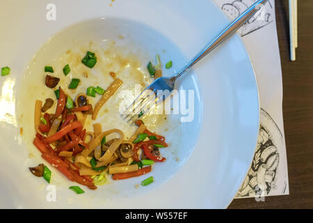 dirty dishes. sauce smeared on a plate. leftovers, pasta, restaurant. didn't finish customers. the view from the top, close up. Stock Photo