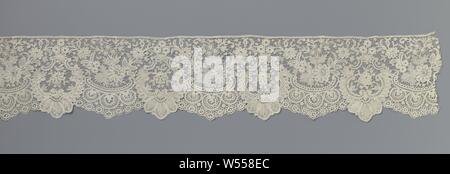 Strip of spool lace with two compositions of c-volutes and daisies, Strip of natural spool of lace: fine Bruges flower arrangements. The repeating pattern consists of two, largely symmetrical compositions of c-volutes and daisies. One composition consists of two c-volutes facing each other along the underside of the strip, which are placed against each other at the bottom. Large increasing lobes are made along the outside of the volutes, the three largest forming a lobed shell. Between the c-volutes are two chalice flowers and a daisy, with a hanging palmetblad above it, topped by three Stock Photo