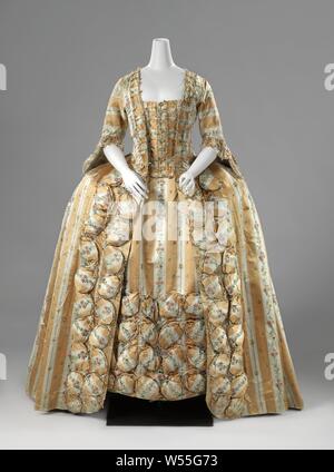 Silk frock or robe à la française with vertical yellow and white stripes and multi-colored bouquets with oval pouffes and lined with a multicolored ikat, frock or robe à la française made of silk with vertical yellow and white stripes and scatter motif multicolored bouquets, with oval pouffes and lined with a multicolored ikat. Model: Square neckline, half-length close-fitting sleeves with engaging and loose-fitting open skirt. The body closes in the front center with nine buttons. To this end, an additional strip of cover has been applied to the inner body of the striped cover, which is Stock Photo