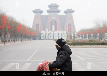 A cyclist wearing face mask against air pollution rides on a road in heavy smog in Taiyuan city, north China's Shanxi province, 26 February 2019. Stock Photo