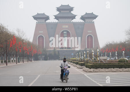 A cyclist wearing face mask against air pollution rides on a road in heavy smog in Taiyuan city, north China's Shanxi province, 26 February 2019. Stock Photo