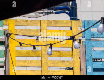 Decorative bulb design, lots of lightbulbs hanging from the cords, creative wooden texture in the background, daytime. Outdoors original modern lights Stock Photo