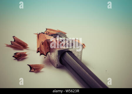 Closeup of sharpening a pencil with a grey metal pencil sharpener with wooden shavings - Concept of school education, learning, student studying Stock Photo