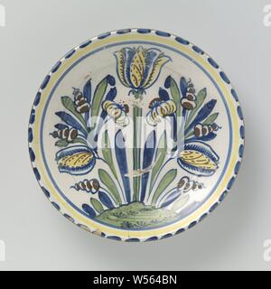 Saucer-dish painted with tulips (?) And leaves, Round dish of multi-colored majolica. The dish is painted with three stylized flowers (tulips?) And leaves on a ground. Along the edge are strokes (blue dashes) painted and a circle. The dish has a wide base, sloping inwards., anonymous, Lambeth, c. 1690 - c. 1700, earthenware, tin glaze, lead glaze, d 30.5 cm × h 5.8 cm Stock Photo
