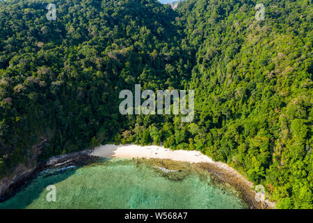 Aerial drone view of a small beach on a lush, green tropical island