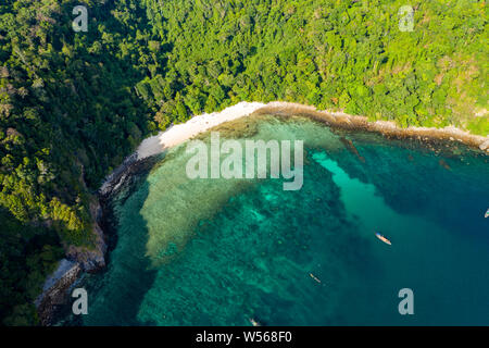 Aerial drone view of a small beach on a lush, green tropical island (Cavern Island)