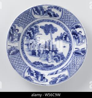 Saucer, painted in blue on the flat with a landscape with a tree and two Chinese figures. Edge adorned with four ovals in which representations, on checkered ground, Round dish of blue painted faience. A landscape with a tree and two figures (Chinese) is painted on the shelf. The border has a checkered background and four oval compartments. In two of the boxes a sitting figure (Chinese) is painted in a landscape and in the other two boxes two figures (Chinese) in a landscape., anonymous, Delft, c. 1650 - c. 1665, earthenware, tin glaze, d 39 cm × h 6 cm Stock Photo