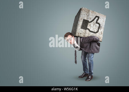 Man bending under a massive stone with a like button on it Stock Photo