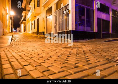 Empty street scene from Old San Juan Puerto Rico at night with buildings and cobblestones. Stock Photo