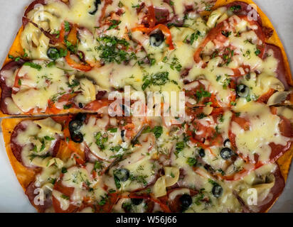 Hunting pizza with sausage, beef, tomatoes and olives on the table. Stock Photo
