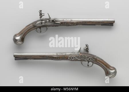 Pair of flintlock pistols Flintlock pistol, Part of a couple. The rooster and the fire steel of the castle are embossed with leaves, the lock plate is engraved with lofwerk, a cupid with a bow and arrow, Cybele in a cart drawn by a lion with four wheels and the signature. The barrel is provided with two pairs of rings as a partition between the different parts of the barrel, the barrel is chiseled on the back with foliage around the rear visor chiseled as a grotesque mask, stamped on the bottom with the arms of Utrecht under an illegible mark, perhaps a rosette. The burr walnut stock is Stock Photo