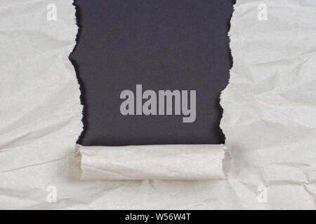 Crumpled package paper torn to reveal black background with copy space Stock Photo