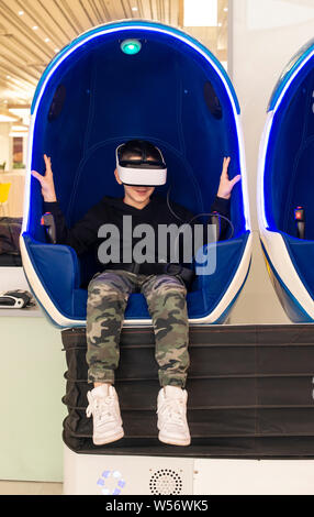 Child watching movie with VR glasses. Blue illuminated cabin with joysticks. Special effects. Technology and entertainment concept with virtual realit Stock Photo