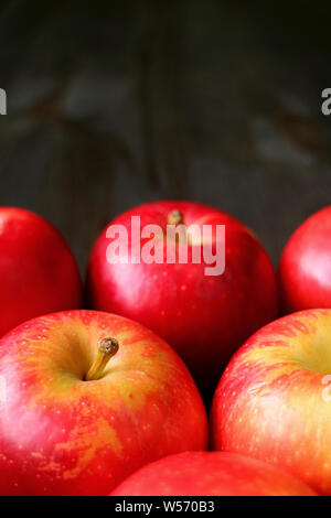 Vertical image of heap of fresh ripe red apples isolated on dark color wooden table with copy space Stock Photo